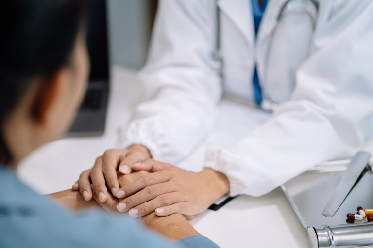 Doctor's hand reassuring elderly patient.
